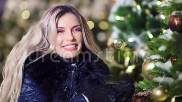 一幅迷人的笑脸女人在圣诞树旁装扮着迷人的晚妆的画像视频的预览图