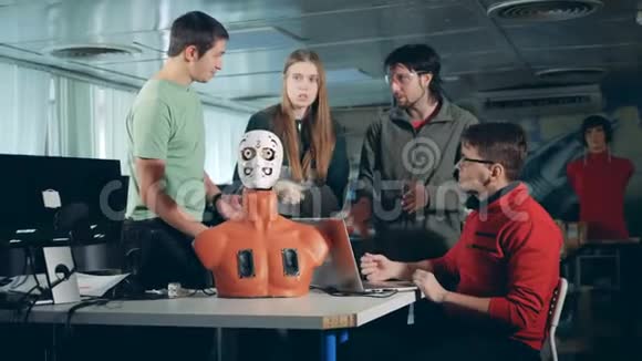 四个工程师和一个人形机器人机器人一起工作视频的预览图