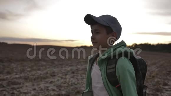 带背包的有趣男孩在户外日落时散步旅行理念视频的预览图