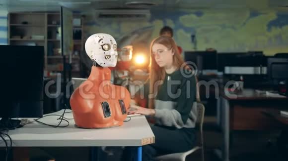 年轻女孩在桌子上控制机器人未来派人形和工程师视频的预览图