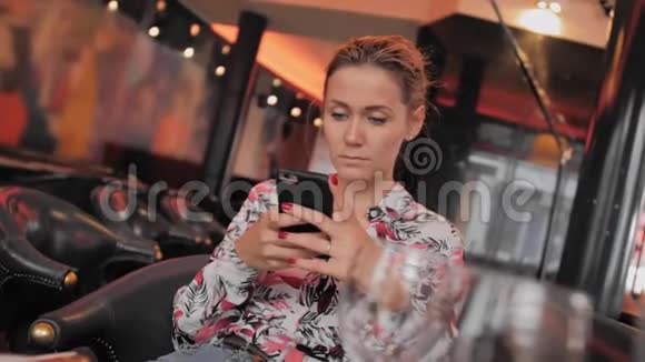年轻的法国女性使用社交网络与手机通信在餐厅里等待你的点菜视频的预览图