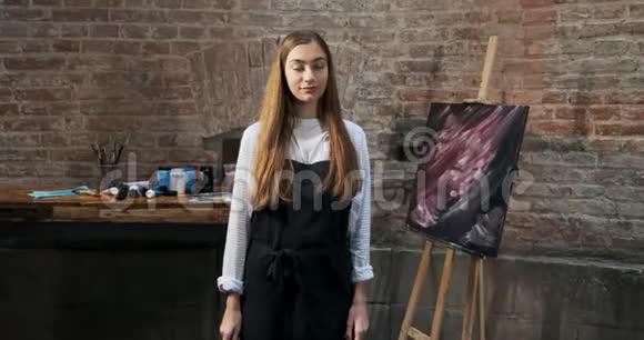 有才华的漂亮女艺术家的肖像与画笔和她的背景画布当代年轻女画家视频的预览图