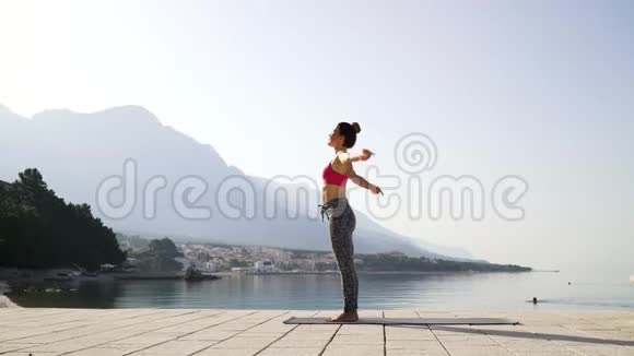 早上在海边练习瑜伽的棕发运动员视频的预览图