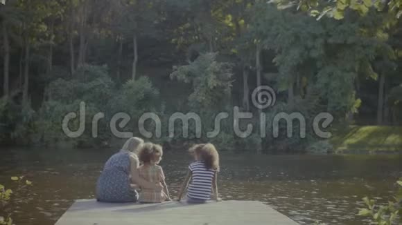 可爱的家庭在池塘边的木墩上放松视频的预览图
