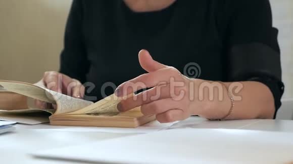 女人在一本悠闲的书中翻阅坐在白色的桌子旁视频的预览图