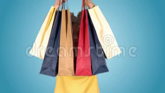 美丽的女孩带着多种颜色的包裹在购物后摆姿势看着相机视频的预览图