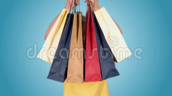 漂亮的女孩带着多种颜色的包裹在购物后摆姿势看着相机视频的预览图