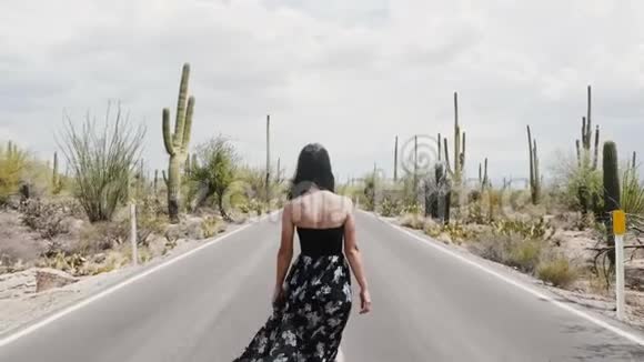 慢镜头跟随年轻的快乐旅游妇女走在炎热的沙漠道路上在萨加罗仙人掌国家公园视频的预览图