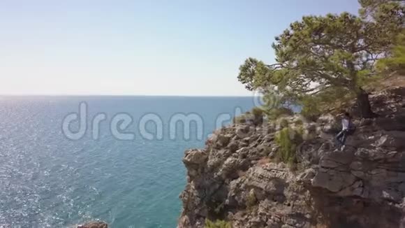 青年旅行者在海边的岩石悬崖上的鸟瞰图视频的预览图