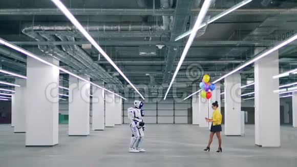 年轻的女人把五颜六色的气球送给一个白色的机器人视频的预览图