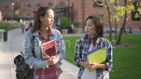 亚洲和白种人大学生在校园里散步谈论教育视频的预览图