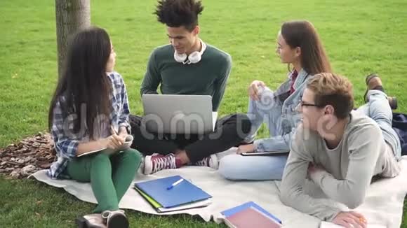 年轻的学生坐在草地上快乐地在一起聊天视频的预览图