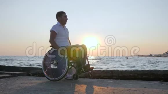 残疾人坐在河堤上的轮椅上残疾人坐在残废的马车上残疾男子视频的预览图