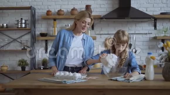 妈妈和女儿正在厨房准备一个馅饼一个女孩把面粉倒进一个大碗里慢动作射击大型视频的预览图