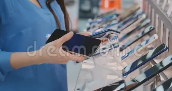 在一家电子商店的橱窗附近买一部新的智能手机时女人的手在挑选视频的预览图