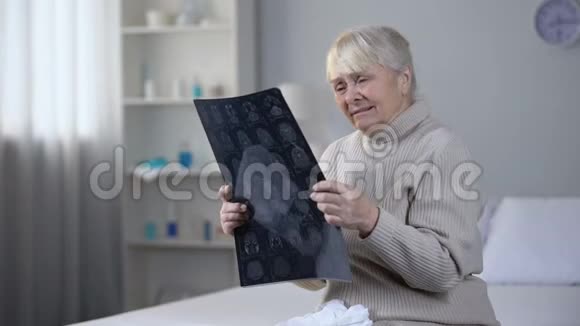 沮丧的老太太看着脑部x光和哭泣不治之症健康视频的预览图