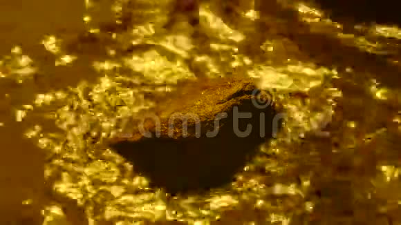 金色的水绕着石头流水波荡漾怒视着河水金色的石头河视频的预览图