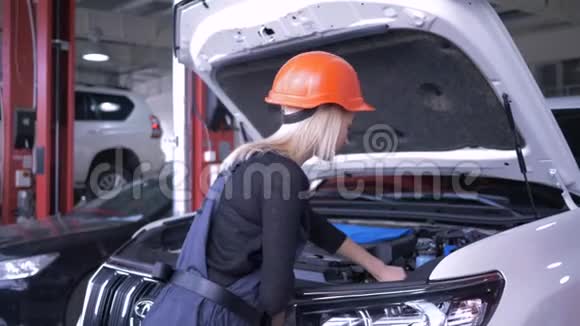 汽修车间女机修工进入安全帽和工作服在服务站用敞篷汽车修理破车视频的预览图