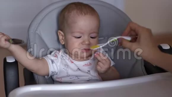 妈妈用勺子喂她可爱的宝宝小男孩正在吃儿童粥视频的预览图