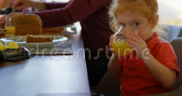 可爱的小男孩在餐桌上喝橙汁4k视频的预览图
