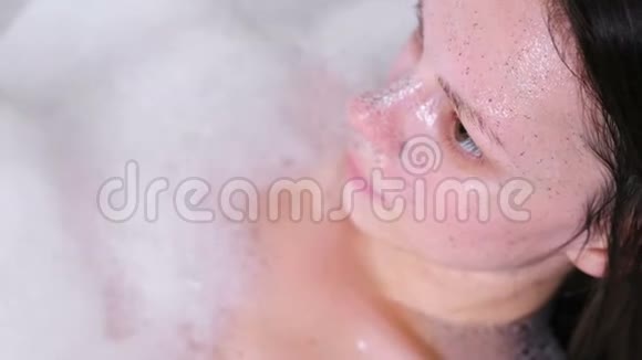 在美丽的黑发女人脸上擦面的特写女人在洗澡视频的预览图