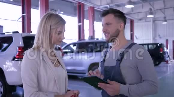 汽车行业车主女士和技术人员在服务站谈论汽车维修视频的预览图