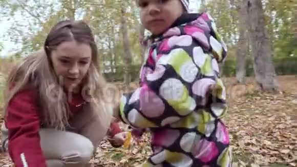 年轻的母亲和她的小女儿在秋天的公园散步视频的预览图