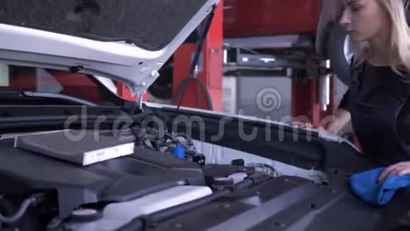 汽车车间幸福女工汽车修理工在汽车维修期间用敞篷罩检查油位视频的预览图