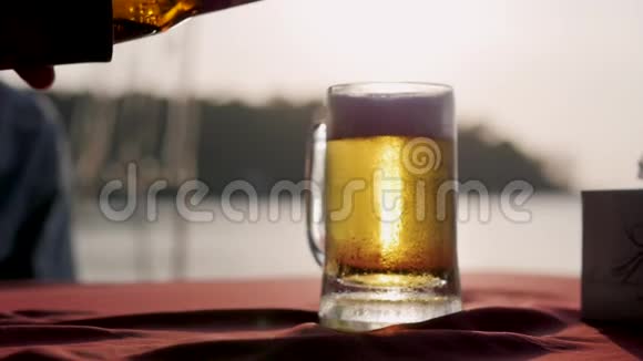 背景中带有夕阳的啤酒杯一个日落时分啤酒从瓶子里倒入杯子视频的预览图