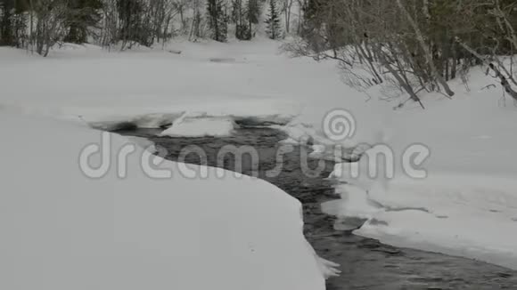 狭窄的水流在白雪堆之间视频的预览图