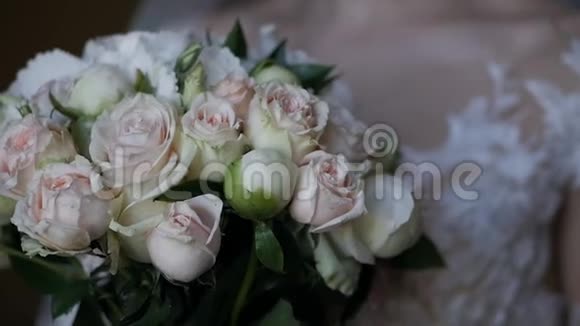 一位身着象牙婚纱的年轻新娘手中捧着一束美丽的婚礼花一束鲜花的特写视频的预览图
