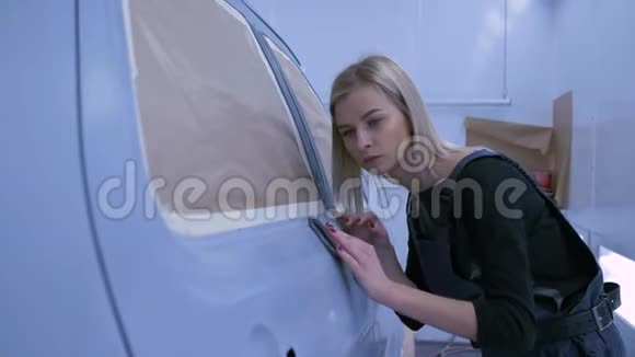 汽车油漆工在修理过程中用手打磨汽车油漆并在油漆室微笑视频的预览图