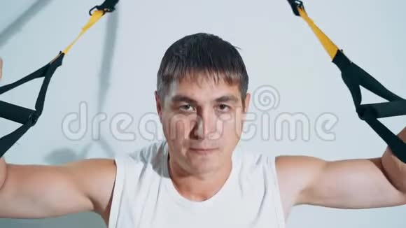 一个男人使用TRX循环参与健身房锻炼胸部肌肉视频的预览图