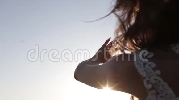 女人看太阳透过她的手掌在日落视频的预览图