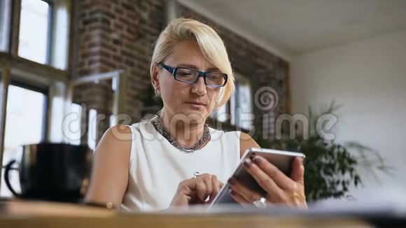 漂亮的商务女性坐在桌子旁在办公室的家里检查电脑平板电脑上的邮件视频的预览图