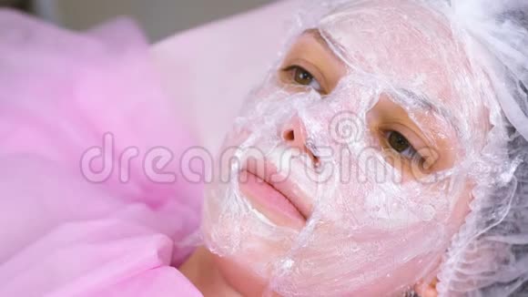 美容师把一张塑料薄膜贴在保湿面膜上面贴在女人脸上视频的预览图