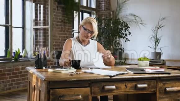 漂亮的女老师正在日记里检查一些东西而坐在办公室的桌子后面喝咖啡视频的预览图