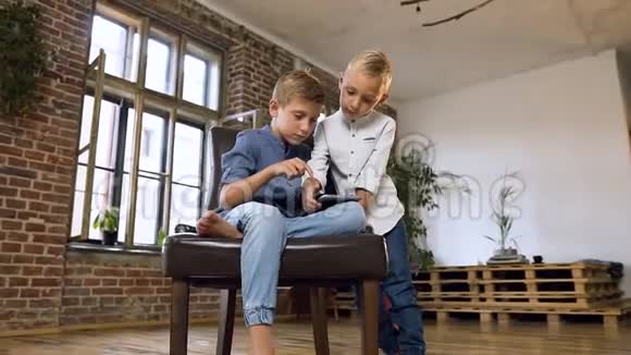 美丽的白种人儿童在平板电脑上玩在线游戏两个十几岁的弟弟玩电脑平板电脑游戏视频的预览图