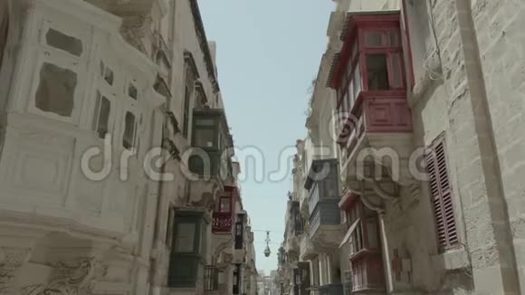 在马耳他瓦莱塔狭窄美丽的老街上向前飞的无人机白色汽车开走了老式阳台4K视频的预览图