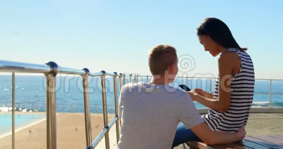 幸福的年轻夫妇在使用靠近栏杆4k的手机时相互交流视频的预览图