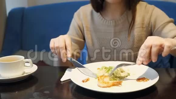 无脸的女人在咖啡馆里用叉子和刀子吃蔬菜沙拉视频的预览图