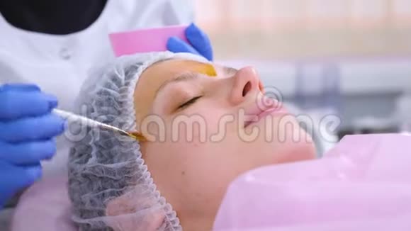 美容师用刷子把女人的脸化学剥落清洁面部皮肤减轻雀斑皮肤视频的预览图