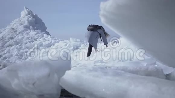 穿着温暖夹克在冰川上行走的年轻女子白雪皑皑的北极或南极令人惊叹的大自然勇敢的女性极地视频的预览图