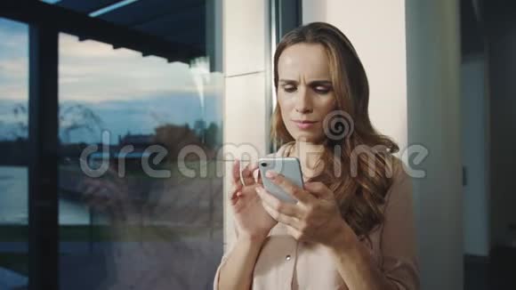 幸福的女人看着手机附近微笑的女人滚动智能手机视频的预览图
