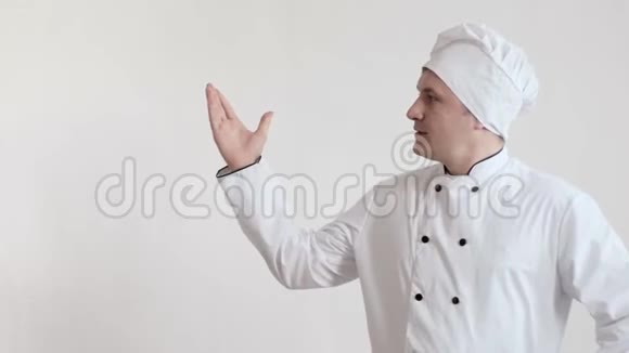 一个穿着厨师衣服和帽子的人站在一个明亮的房间里腰深深地站在他面前看着他的手视频的预览图