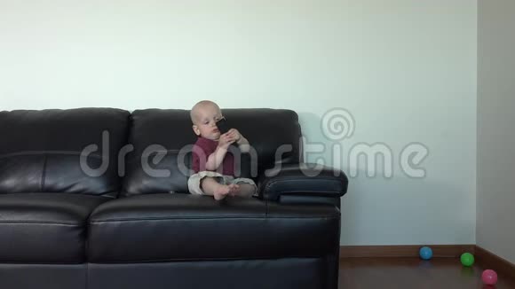 有趣的小男孩坐在沙发上用遥控器视频的预览图