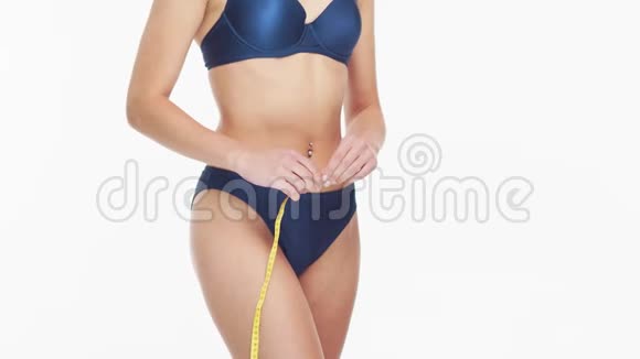 年轻美丽健康自然的女人穿着蓝色泳衣在孤立的白色背景下测量她完美的身体视频的预览图