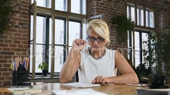 漂亮的戴眼镜的忙碌女人在办公室办公桌后面的日记里记录了一些东西印支商务视频的预览图