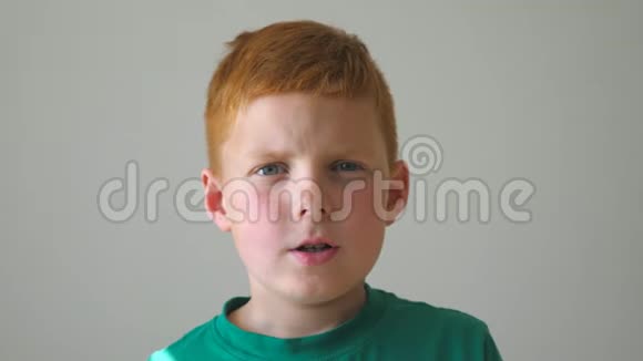 年轻的孩子看着相机触摸他的脸表达了绝望有雀斑的红发男孩的肖像视频的预览图