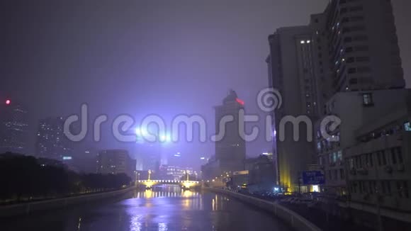 沿河的摩天大楼在夜间照亮了周围的广告标志中国上海视频的预览图